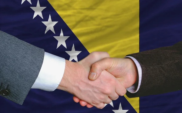 Uomini d'affari stretta di mano dopo un buon affare di fronte alla bandiera bosnia erbe — Foto Stock