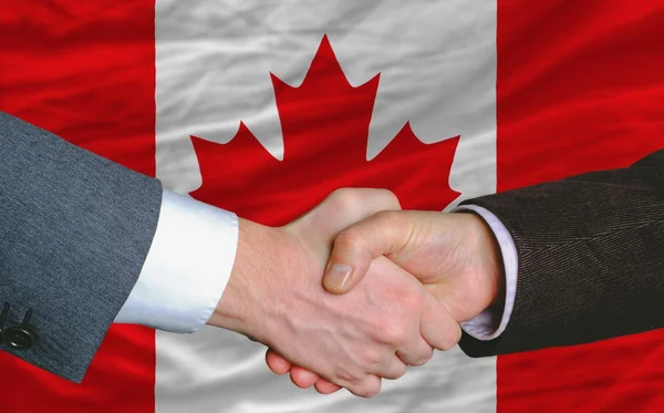 Homens de negócios handshakeafter bom negócio na frente da bandeira do Canadá — Fotografia de Stock