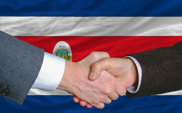 Hombres de negocios apretón de manos después de un buen trato frente a la bandera de Costa Rica — Foto de Stock