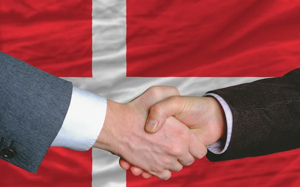 Empresarios apretón de manos después de un buen trato delante de la bandera de Dinamarca — Foto de Stock