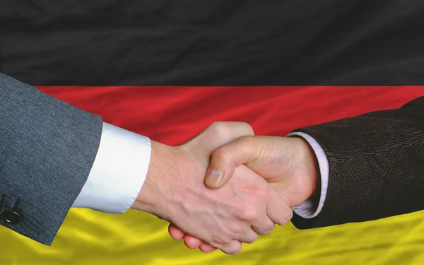 Gli uomini d'affari si stringono la mano dopo un buon affare davanti alla bandiera tedesca — Foto Stock