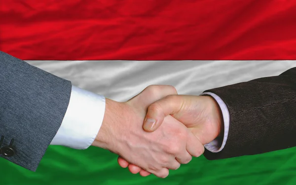 Des hommes d'affaires serrent la main après une bonne affaire devant le drapeau hongrois — Photo