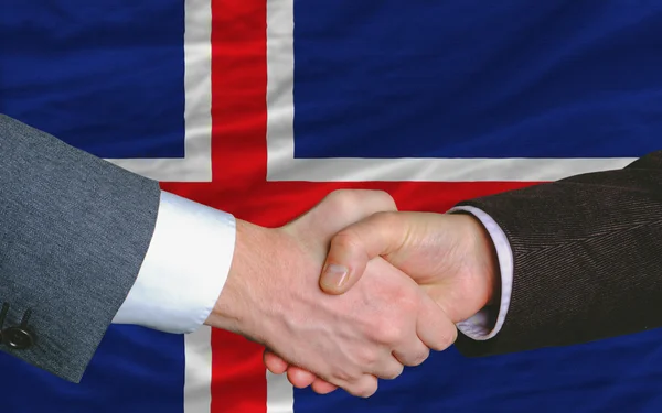 Geschäftsleute geben sich nach dem Deal vor der isländischen Flagge die Hand — Stockfoto