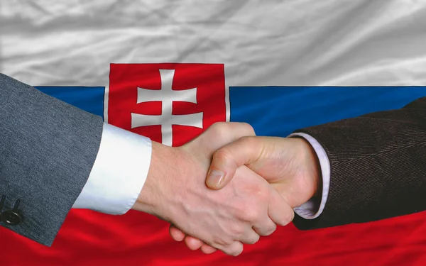Gli uomini d'affari stringono la mano dopo un buon affare davanti alla bandiera slovacca — Foto Stock