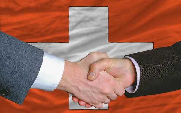Gli uomini d'affari si stringono la mano dopo un buon affare davanti alla bandiera svizzera — Foto Stock