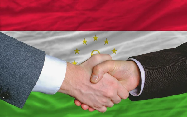Businessmen handshake after good deal in front of tajikistan fla — Stock Photo, Image