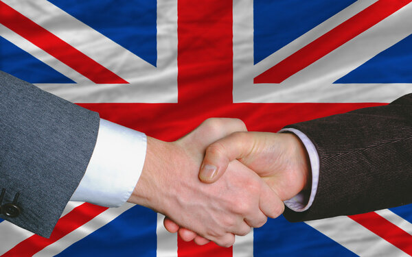 Businessmen handshake after good deal in front of uk flag