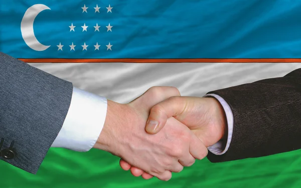 Podnikatelé handshake po hodně před Uzbekistán fla — Stock fotografie