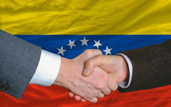 Negocios apretón de manos después de un buen trato frente a la bandera de venezuela —  Fotos de Stock