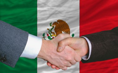 Businessmen handshake after good deal in front of mexico flag clipart