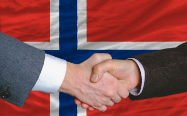 Businessmen handshake after good deal in front of norway flag clipart