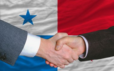 Businessmen handshake after good deal in front of panama flag clipart