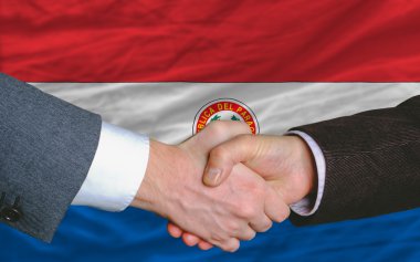 Businessmen handshake after good deal in front of paraguay flag clipart
