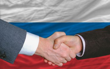 Businessmen handshake after good deal in front of russia flag clipart