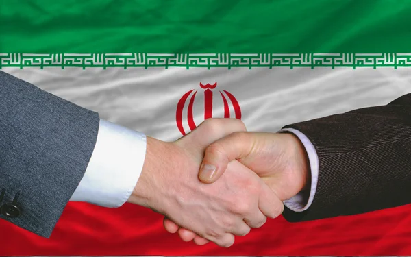 Деловые люди пожали друг другу руки после хорошей сделки перед иранским флагом — стоковое фото