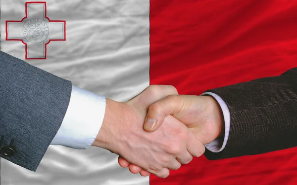 Geschäftsleute geben sich nach einem guten Geschäft vor der maltesischen Flagge die Hand — Stockfoto