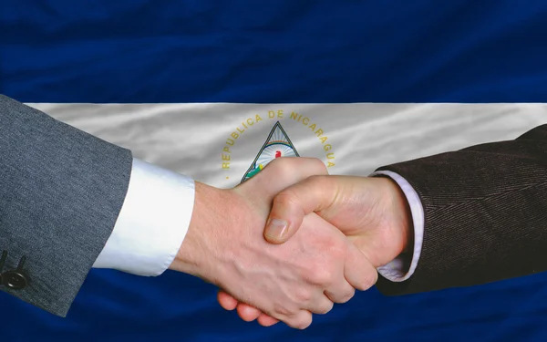 Деловые люди пожали друг другу руки после хорошей сделки перед флагом Никарагуа — стоковое фото