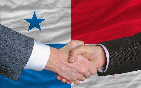 Empresários aperto de mão depois de um bom negócio na frente da bandeira do Panamá — Fotografia de Stock