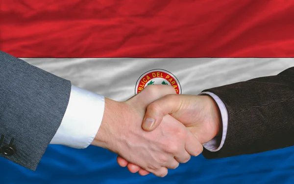 Negocios apretón de manos después de un buen trato frente a la bandera del paraguay — Foto de Stock