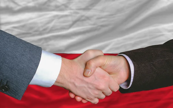 Empresários aperto de mão após bom negócio na frente da bandeira da Polônia — Fotografia de Stock