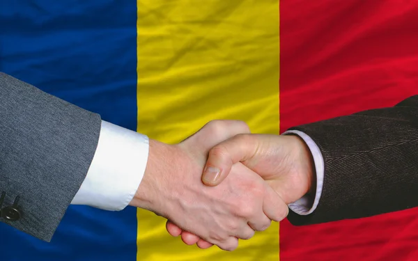 Empresários aperto de mão depois de um bom negócio na frente da bandeira romania — Fotografia de Stock