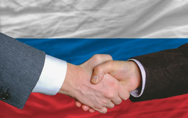 Gli uomini d'affari si stringono la mano dopo un buon affare davanti alla bandiera russa — Foto Stock