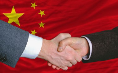 Businessmen handshakeafter good deal in front of china flag clipart