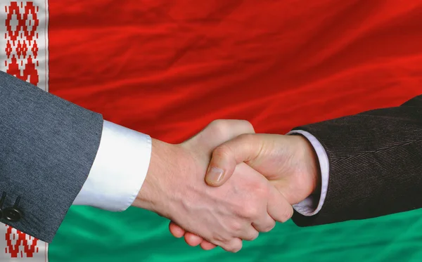 Homens de negócios handshakeafter bom negócio na frente da bandeira belarus — Fotografia de Stock