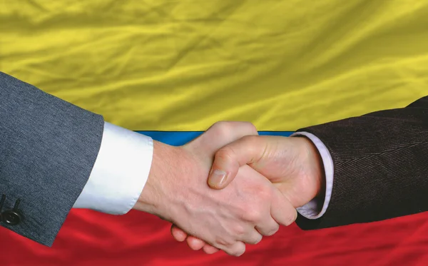 Homens de negócios handshakeafter bom negócio na frente da bandeira da Colômbia — Fotografia de Stock