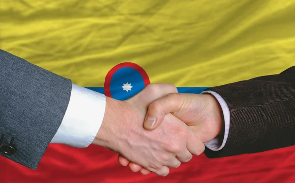 Hombres de negocios apretón de manos después de un buen trato delante de la bandera de Colombia —  Fotos de Stock