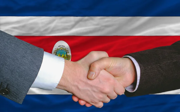 Hombres de negocios apretón de manos después de un buen trato frente a la bandera de Costa Rica —  Fotos de Stock