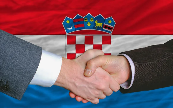 Hombres de negocios apretón de manos después de un buen trato frente a la bandera de Croacia — Foto de Stock