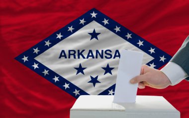 Man voting on elections in front of flag US state flag of arkans clipart