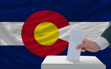 Man voting on elections in front of flag US state flag of colora clipart