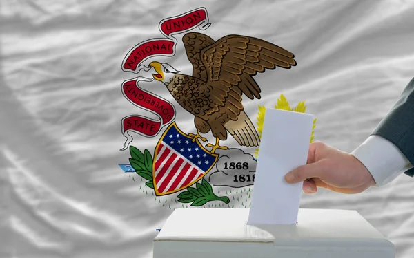 Uomo che vota per le elezioni davanti alla bandiera degli Stati Uniti bandiera di stato di Illino — Foto Stock