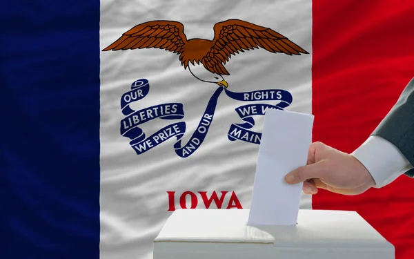 Hombre votando en elecciones frente a bandera Bandera del estado de Iowa — Foto de Stock