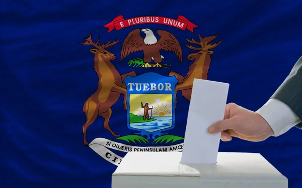 Man röstar om valet framför flagga oss statligt flagga michig — Stockfoto