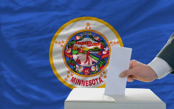 Hombre votando en las elecciones frente a la bandera Bandera del estado de Estados Unidos de Minnes —  Fotos de Stock