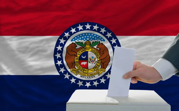 Hombre votando en las elecciones frente a la bandera de Estados Unidos bandera de missou — Foto de Stock