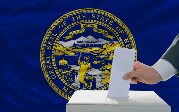 Homem votando em eleições em frente à bandeira bandeira do estado dos EUA de nebras — Fotografia de Stock