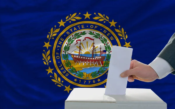 Man voting on elections in front of flag US state flag of new ha — Stock Photo, Image