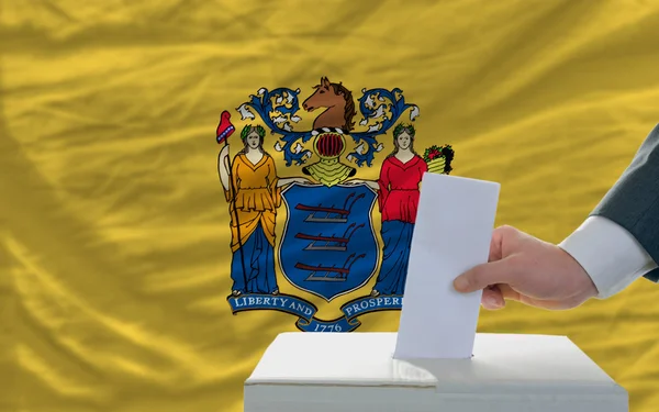 Человек голосование на выборах перед флагом США флаг штата Нью-Джерси — стоковое фото