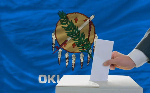 Мужчина голосует на выборах перед флагом американского штата Оклахо — стоковое фото