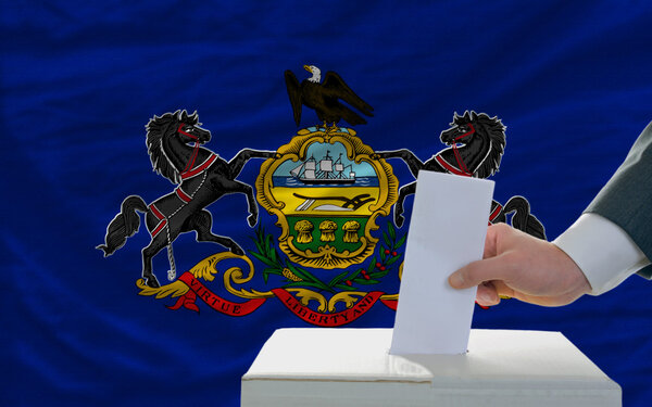 Man voting on elections in front of flag US state flag of pennsy