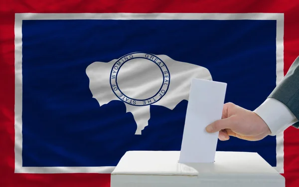 Muž hlasování o volbách před vlajkou nás státní vlajka wyomin — Stock fotografie