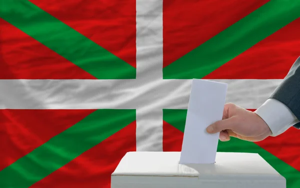 Man röstar om valet framför flaggan baskiska — Stockfoto