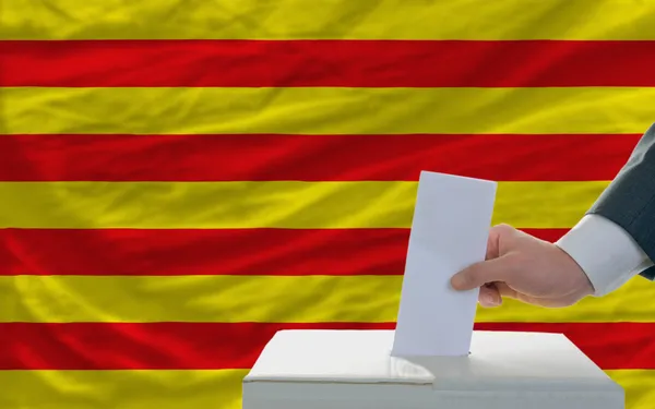 Hombre votando en elecciones frente a bandera nacional de catalonia — Foto de Stock