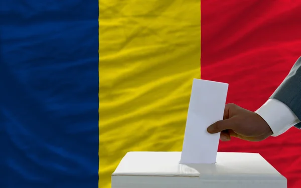 Hombre votando en las elecciones frente a la bandera nacional de Chad — Foto de Stock