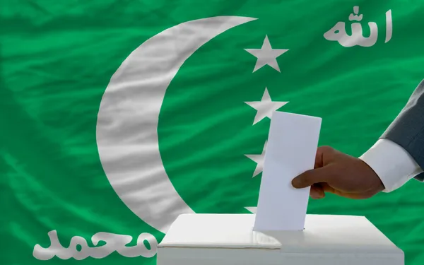 Homem votando nas eleições em frente à bandeira nacional de comorbidades — Fotografia de Stock