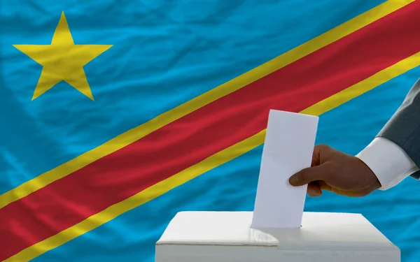 Homem votando nas eleições em frente à bandeira nacional do Congo — Fotografia de Stock